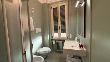 A compact bathroom with a toilet, a sink, and a window.