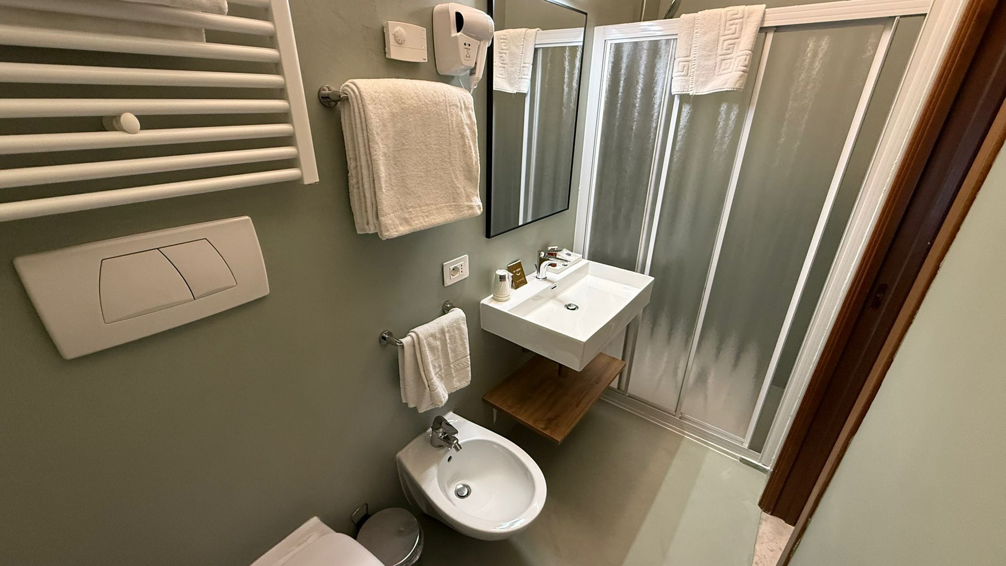 Une salle de bain moderne avec un grand miroir, un lavabo, un bidet et un porte-serviettes.