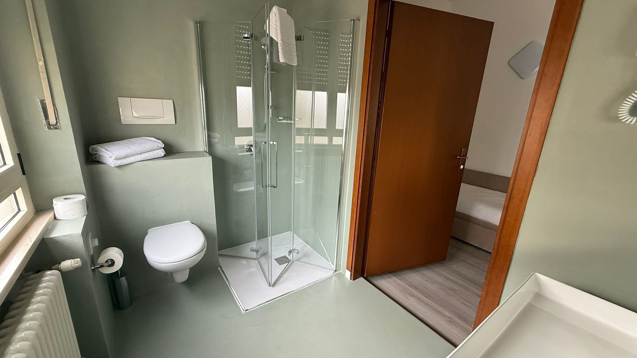 Une salle de bain comprenant des toilettes, une douche en verre et un porte-serviettes.