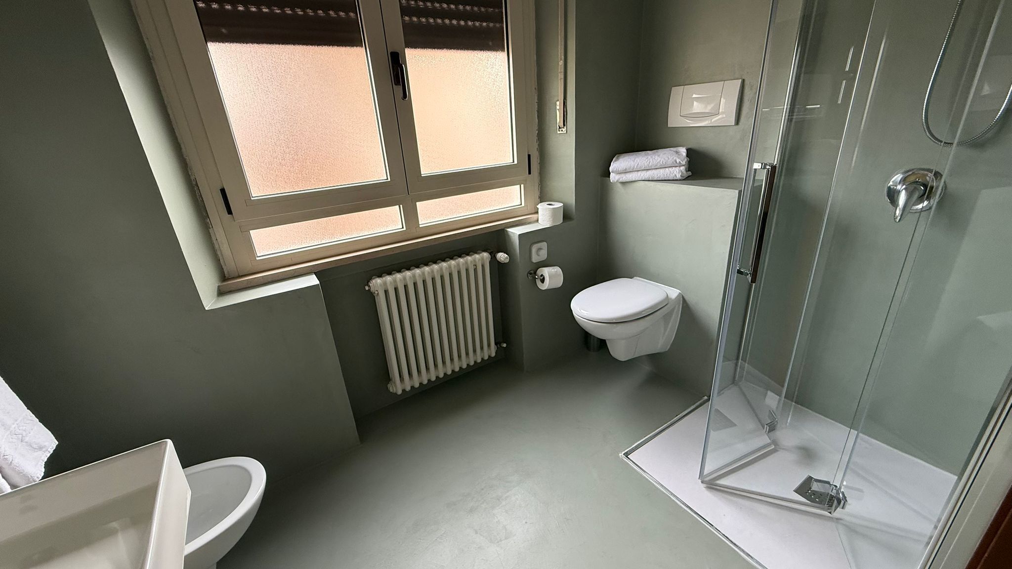 Un baño pequeño con inodoro, cabina de ducha y ventana que proporciona luz natural.