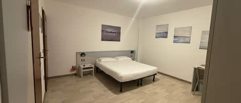 A bedroom with a bed, a nightstand, a wall-mounted lamp, and a ceiling light.