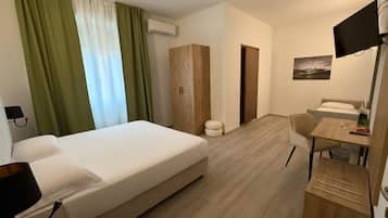 A hotel room with a bed, a desk, a chair, a television, and a wardrobe.