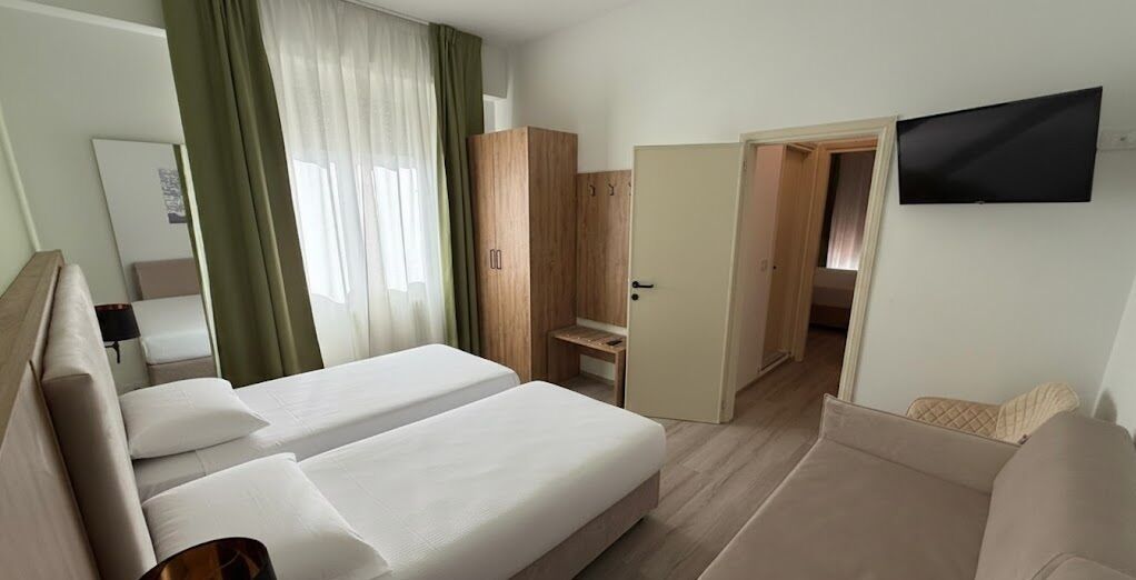 Une chambre d’hôtel avec deux lits, une télévision, une armoire et un bureau.