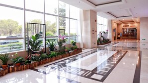 A spacious lobby with large windows, a polished floor, and a variety of indoor plants. - Southern Airlines Pearl Hotel (Guangzhou)
