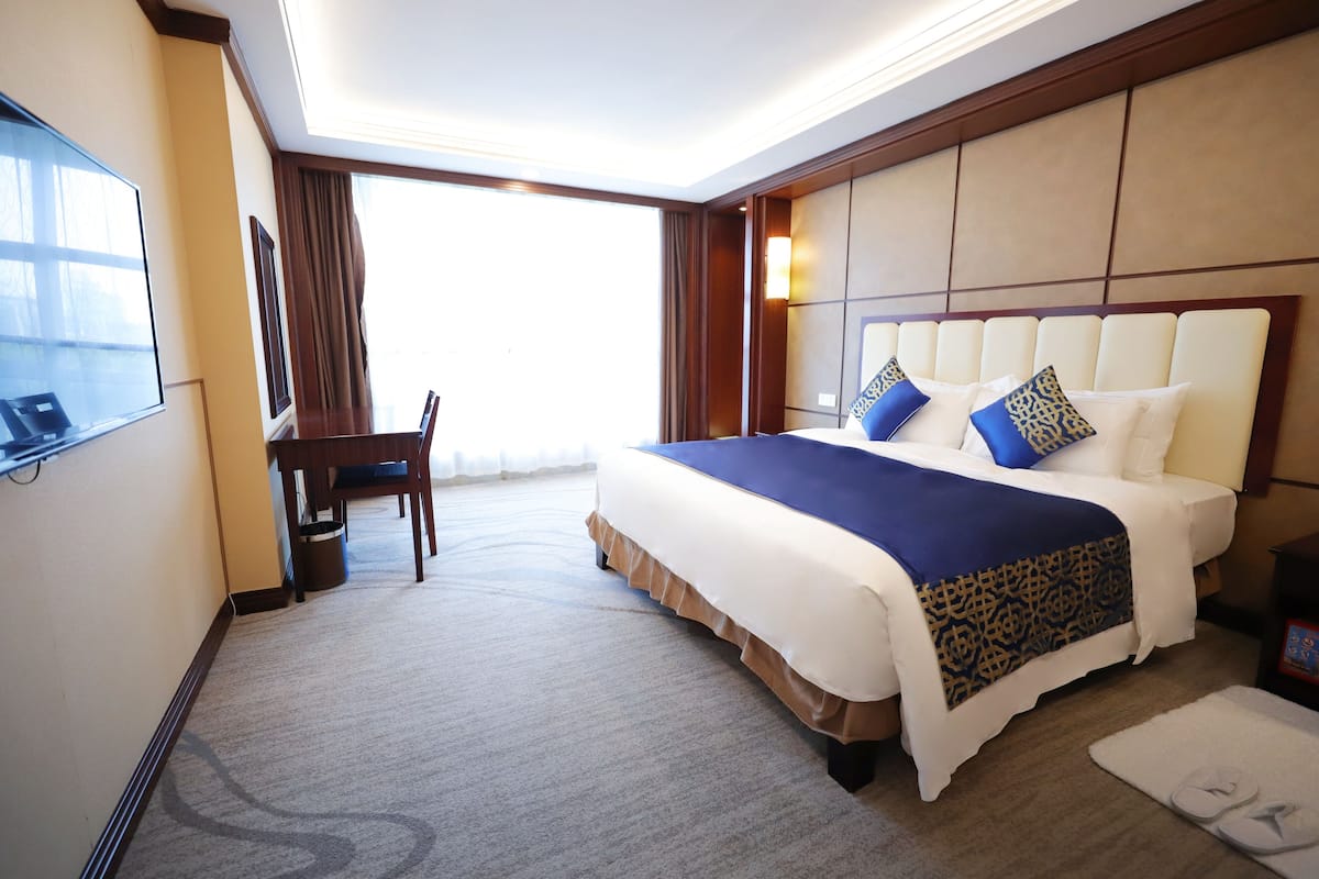Une chambre d’hôtel avec un grand lit, un bureau et une télévision.