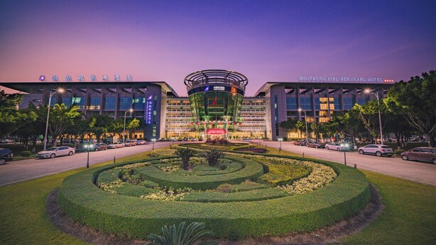 A modern hotel with a circular central feature, surrounded by a landscaped garden. - Southern Airlines Pearl Hotel (Guangzhou)