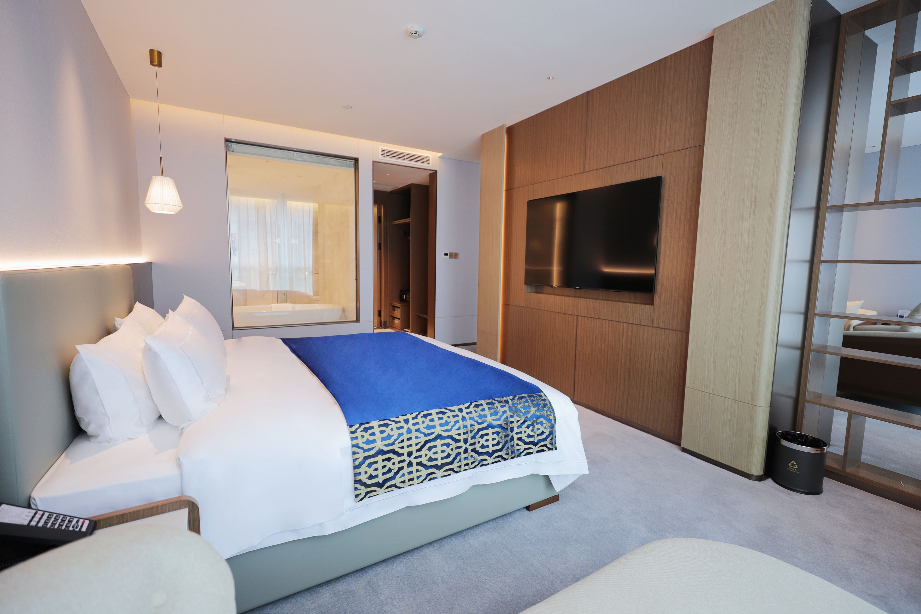 Une chambre d’hôtel moderne dotée d’un grand lit, d’un téléviseur fixé au mur et d’un dressing.