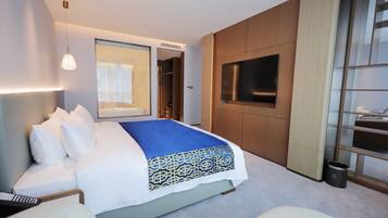 Une chambre d’hôtel moderne dotée d’un grand lit, d’un téléviseur fixé au mur et d’un dressing.