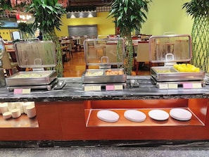 Un espace buffet avec différents récipients et assiettes contenant de la nourriture.