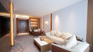 A modern living room with a sofa, coffee table, and TV. There is a dining area with chairs and a table. - Southern Airlines Pearl Hotel (Guangzhou)