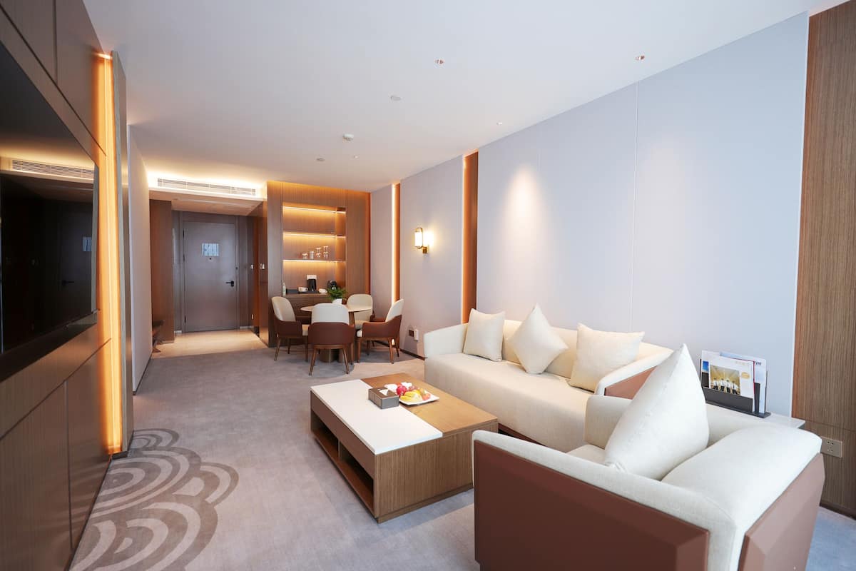 Un salon moderne avec un canapé, une table basse et un téléviseur. Il y a également un coin repas avec des chaises et une table.