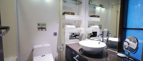 A modern bathroom with a white toilet, a sink with a glass shelf above, and a mirror.