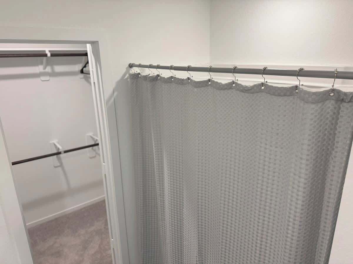 A bathroom with a shower curtain, a towel rack, and a door.