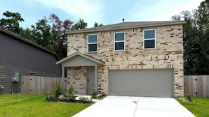 A two-story house with a garage, a front porch, and a well-maintained lawn.