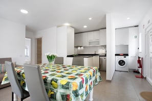 Un appartement moderne comprenant un coin repas, une cuisine et un espace buanderie.
