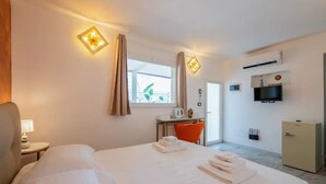 Hotellihuone, jossa on sänky, työpöytä, tuoli, televisio ja minibaari.