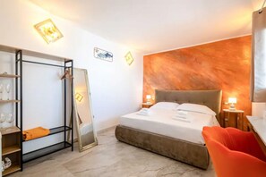Habitación de hotel con cama, armario, espejo, silla y pared con diseño texturizado.