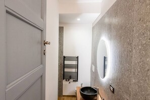Een moderne badkamer met een grote spiegel, een zwarte wastafel en een handdoekrek.