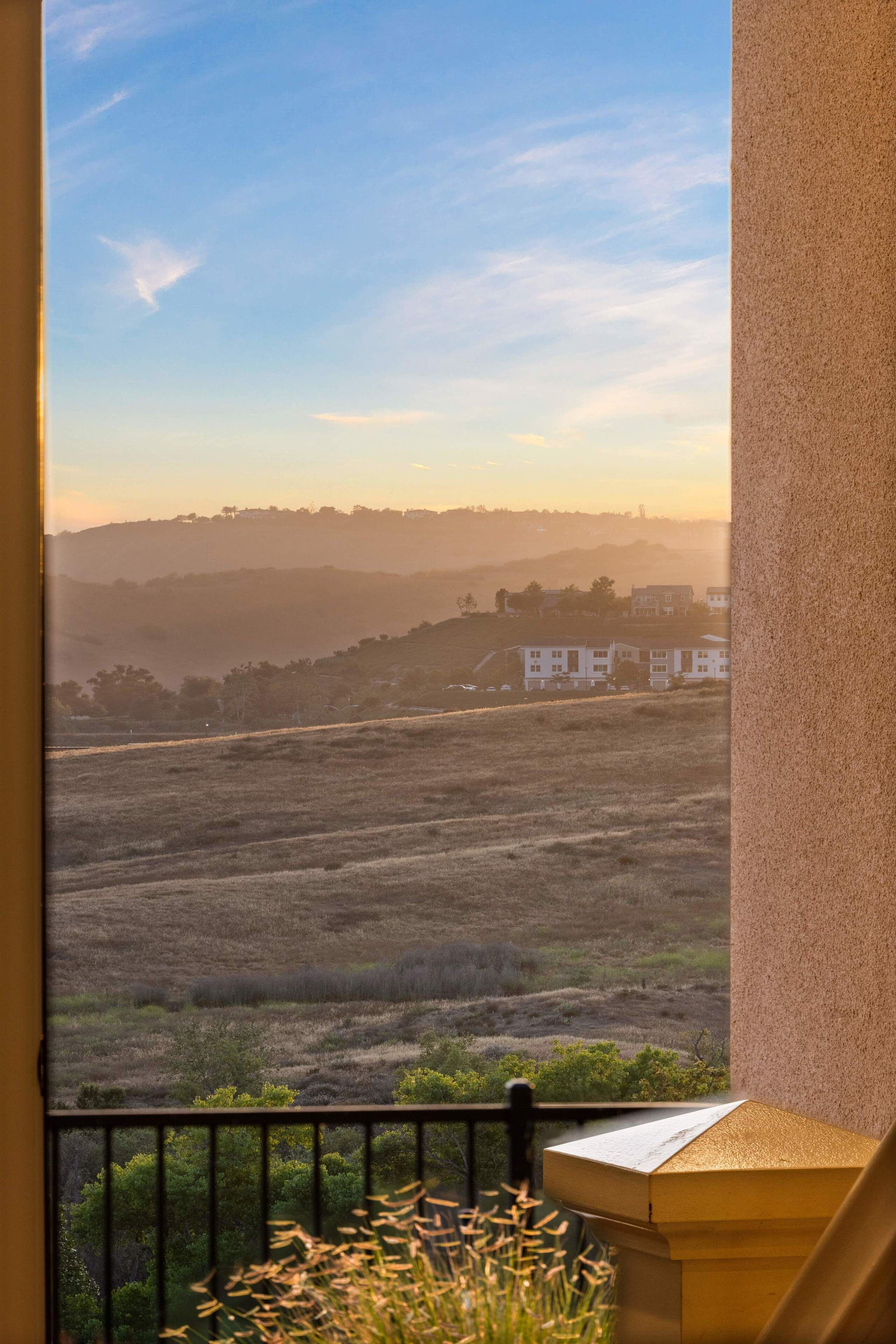 Un balcón con vistas a un paisaje montañoso y edificios a lo lejos.