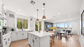 A modern kitchen with white cabinetry, a central island, and pendant lighting. - @ Marbella Lane - Curated 5BR in Upscale RMV Haven (San Juan Capistrano)