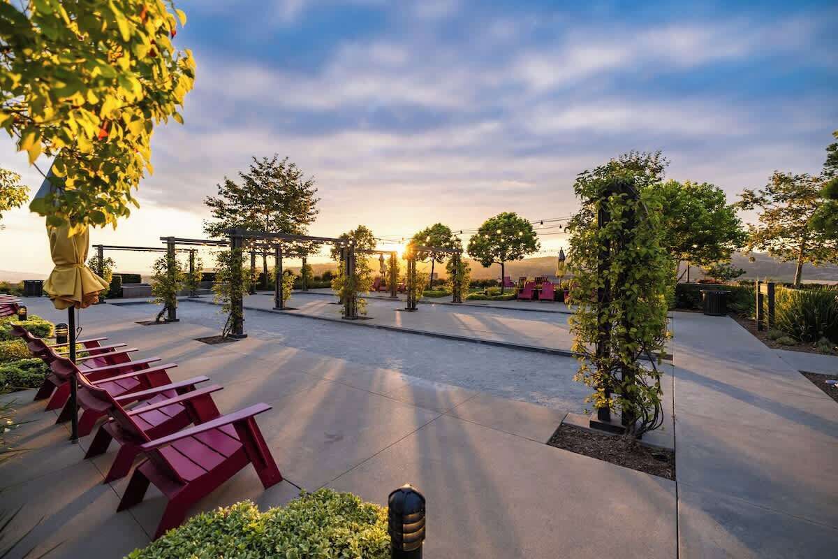 Un espacio al aire libre con sillas rojas y una estructura de pérgola.