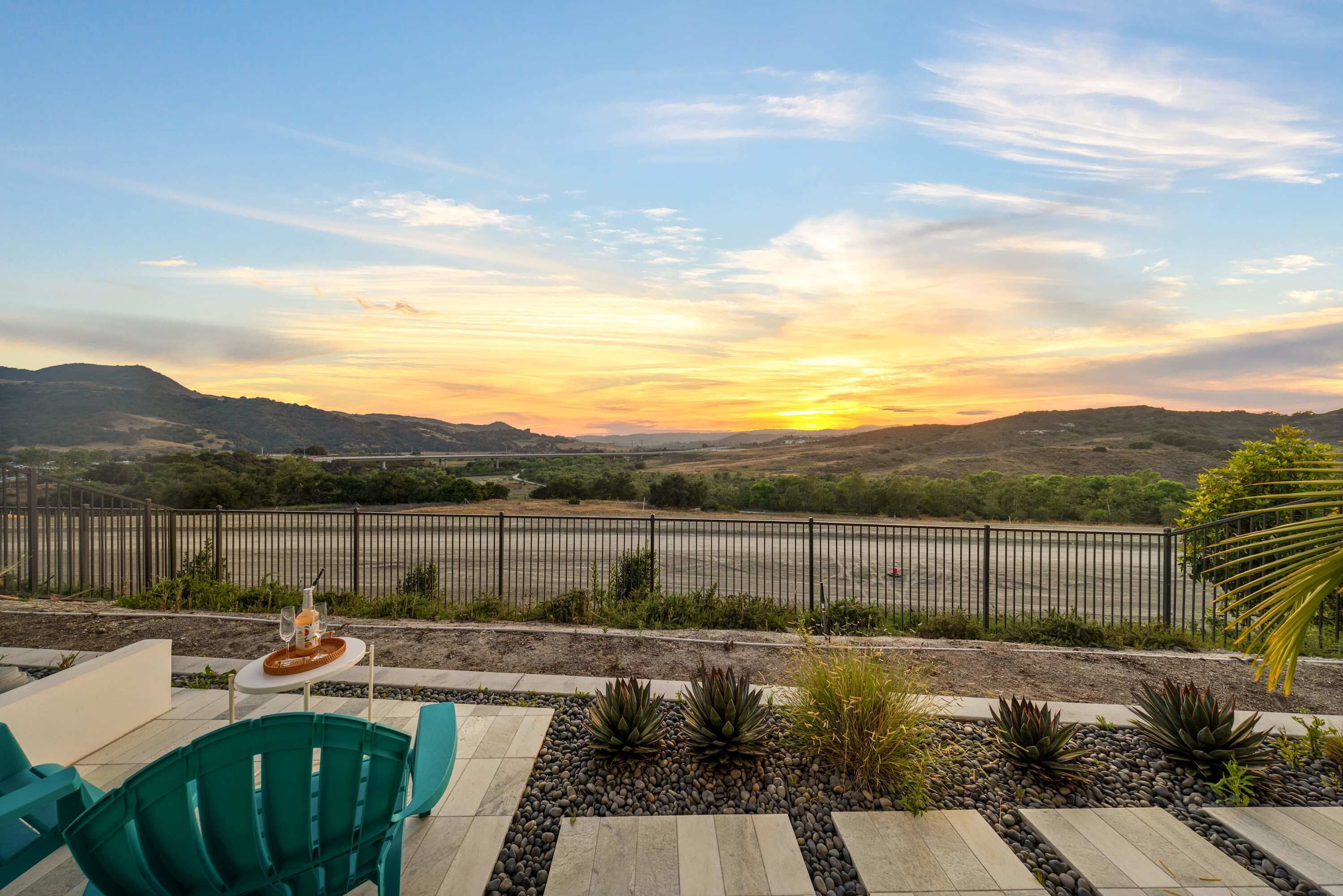 Een terras met een tafel gedekt voor twee, met uitzicht op een schilderachtige omgeving met heuvels en een zonsondergang.