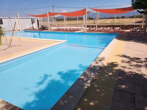 Una piscina rettangolare con superficie d'acqua cristallina, circondata da un solarium piastrellato.