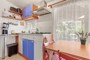 Una cucina compatta con piano cottura a gas, macchina del caffè e zona pranzo con tavolo e sedie.