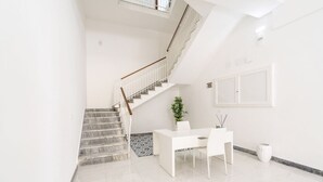 A modern interior with a staircase, a white reception desk, and a potted plant. - Simona - Italian Living (Monopoli)