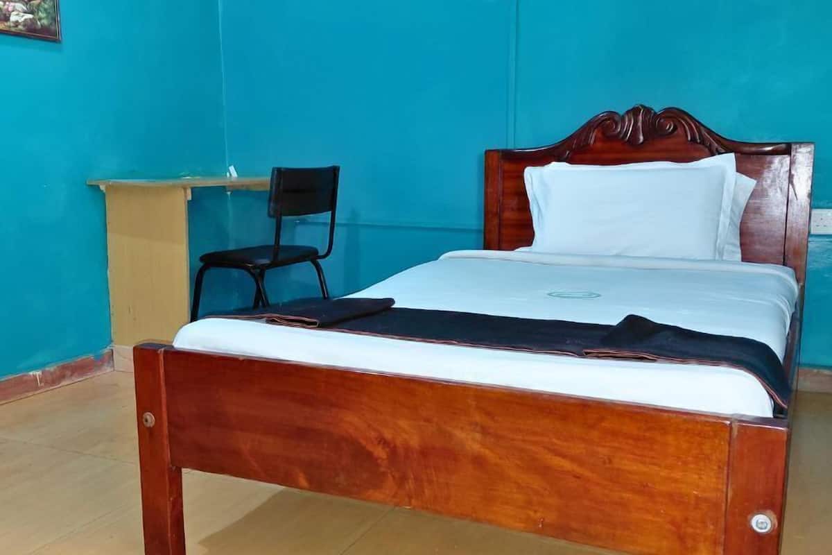 A single bed with a wooden frame and white bedding in a room with blue walls and a wooden floor.