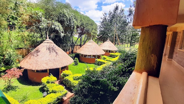 Vista d'un jardí exuberant amb cabanes de teules, envoltat de vegetació densa i un cel clar.