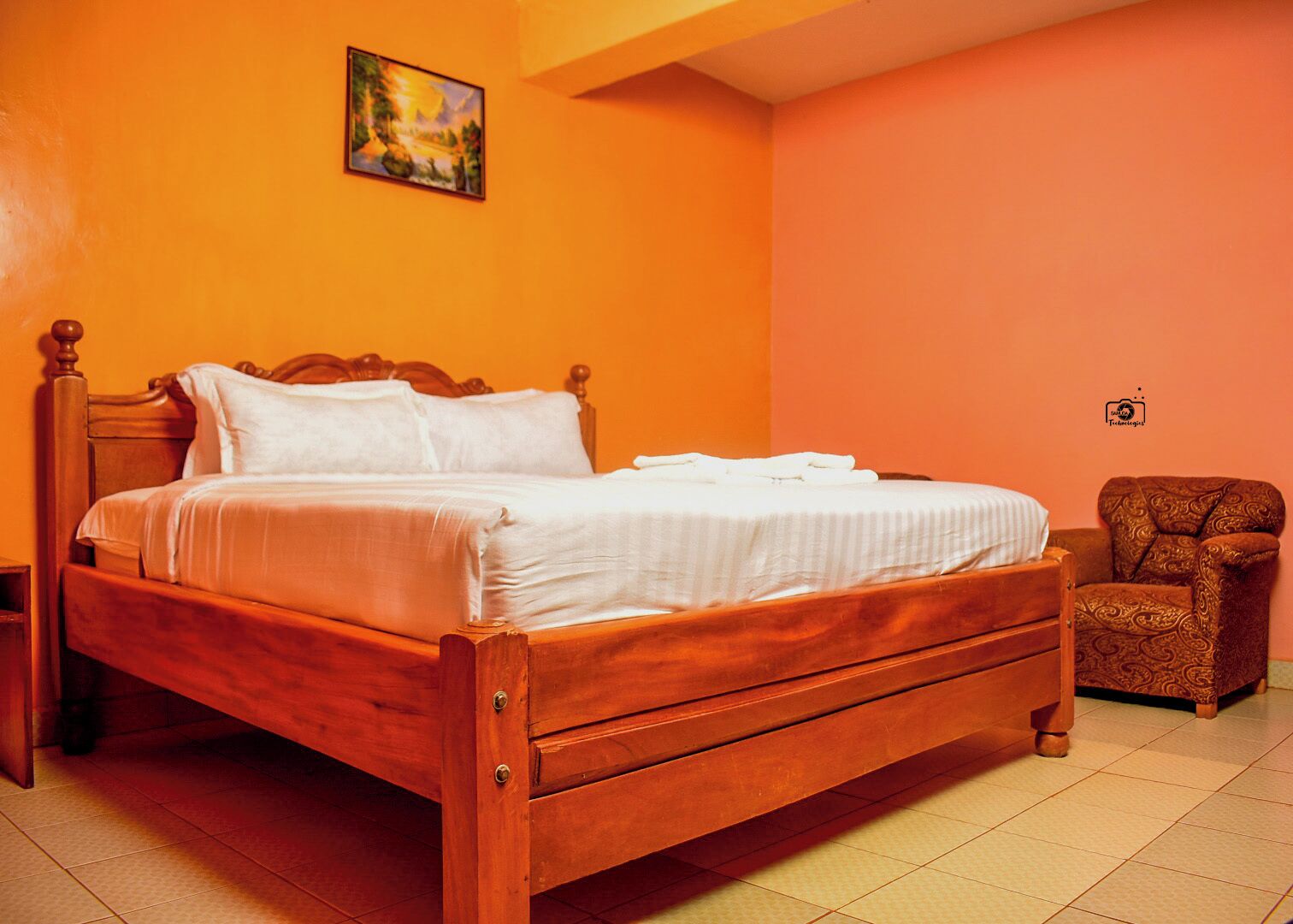 Un dormitorio con una cama de madera, una silla y un cuadro en la pared.