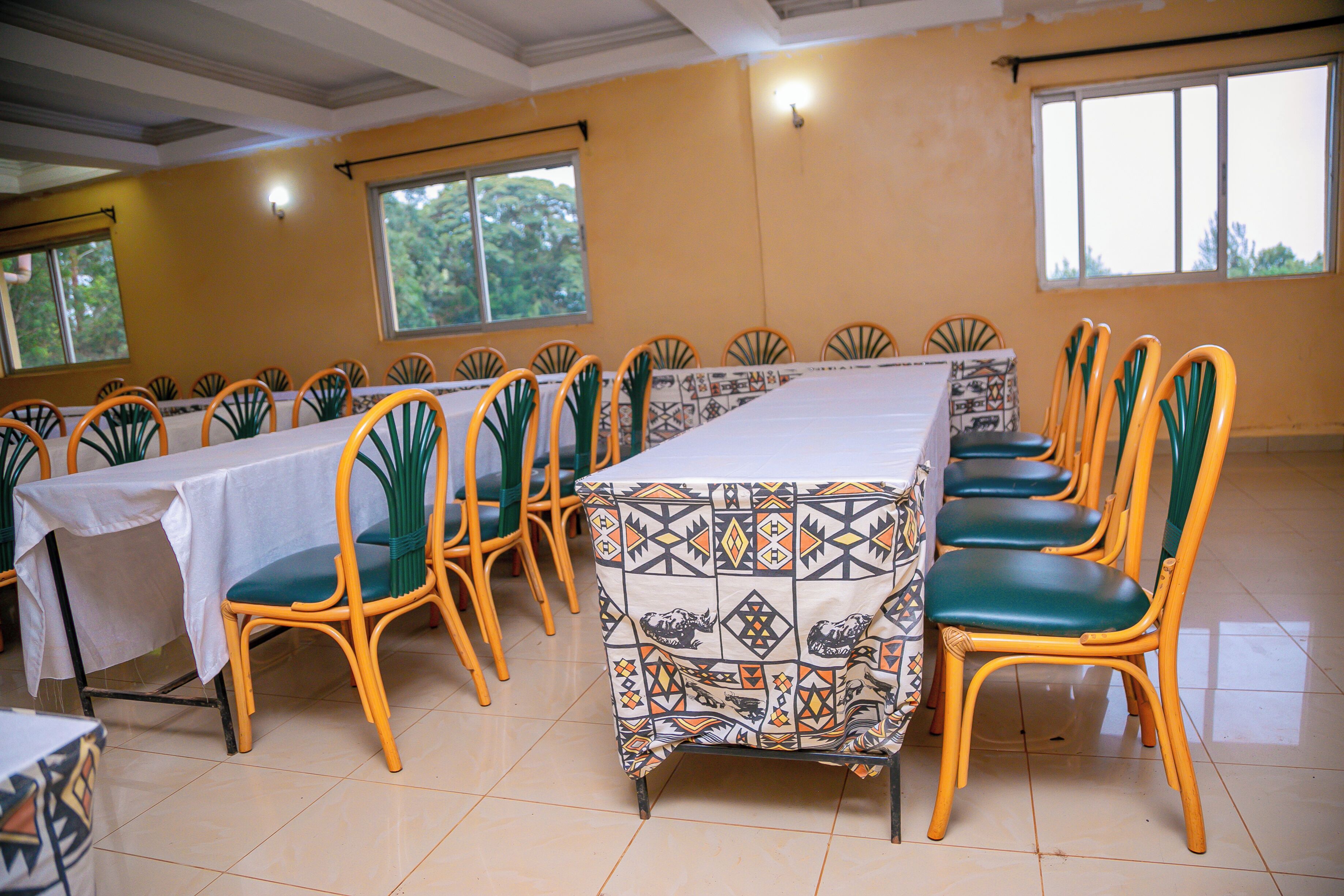 A dining area with multiple tables and chairs, large windows, and a tiled floor.