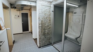 A hallway with a patterned floor, a stone wall, and a glass elevator door. - STB Campus Bartholomä (Bartholomä)