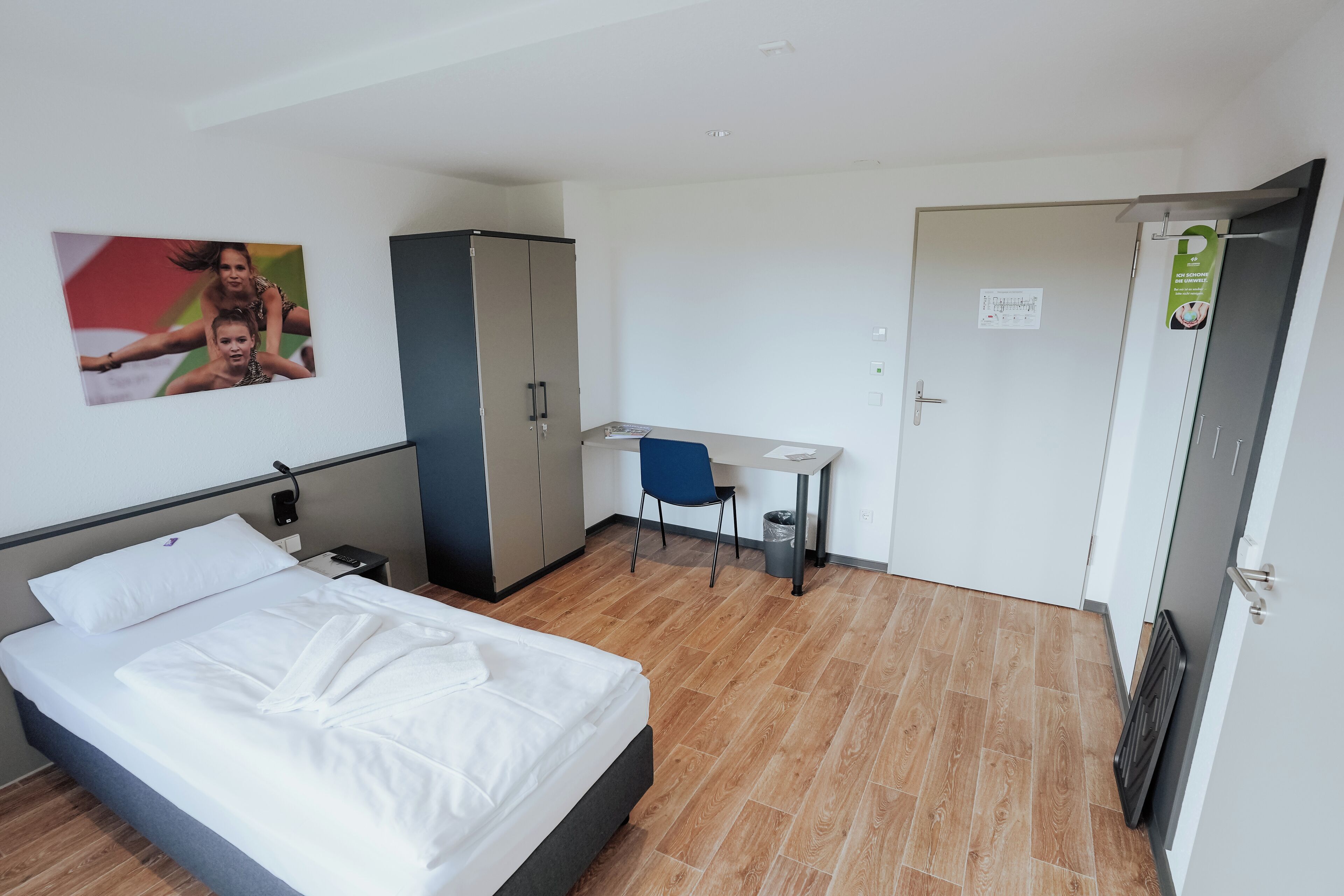 Una camera d'albergo con un letto, una scrivania, una sedia e un armadio.