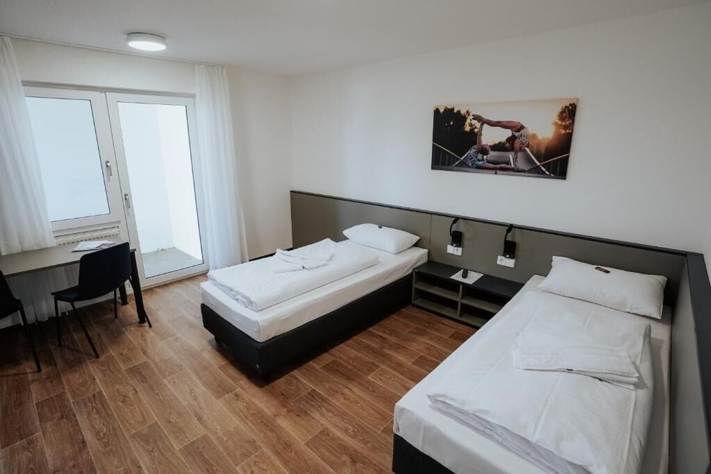Une chambre d’hôtel avec deux lits, un bureau et une chaise.