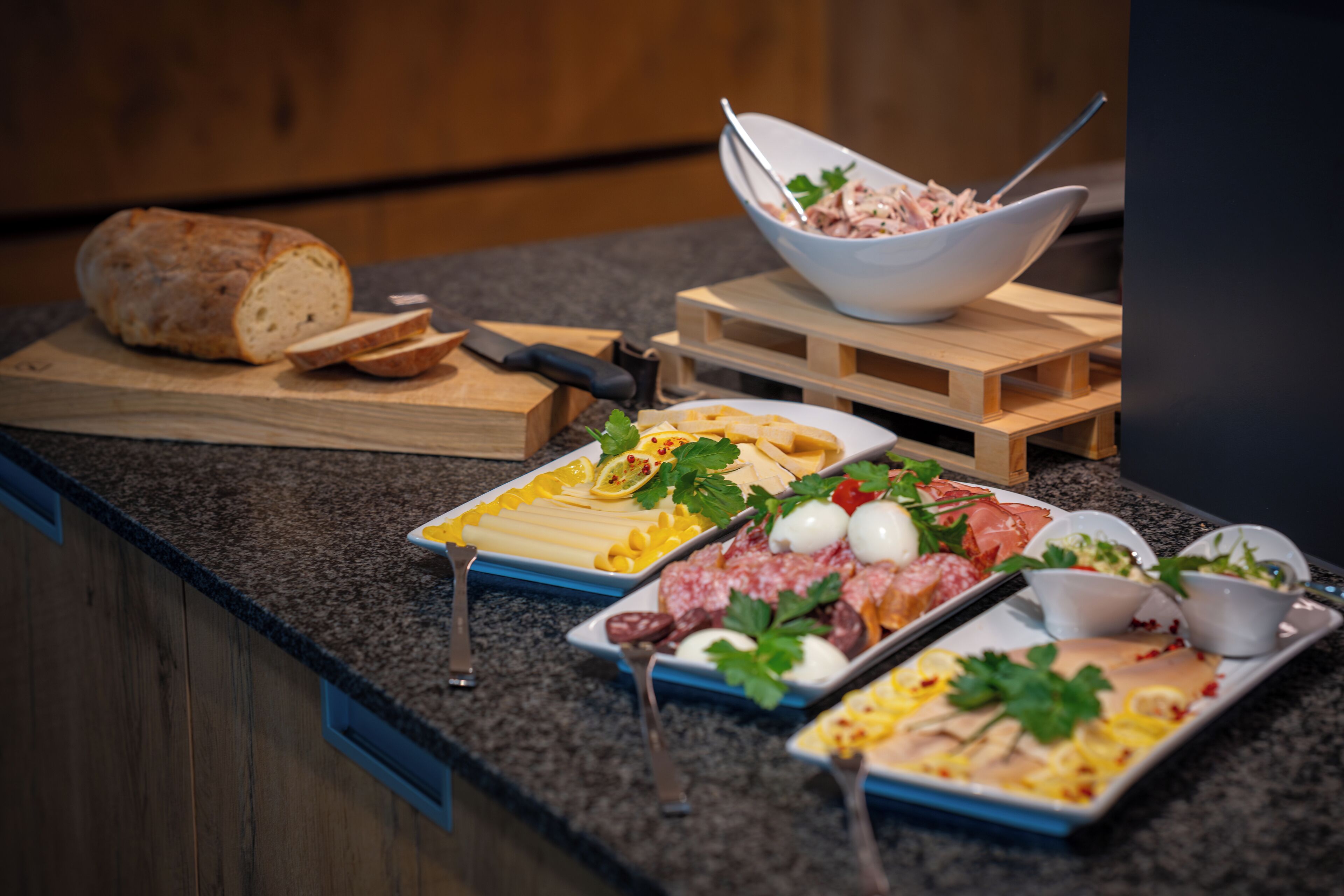 Ein Buffet mit verschiedenen Speisen, darunter Brot, Käse, Fleisch und Beilagen.