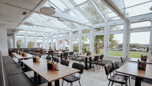 A spacious indoor area with long tables and chairs, large windows, and a view of the outdoors. - STB Campus Bartholomä (Bartholomä)