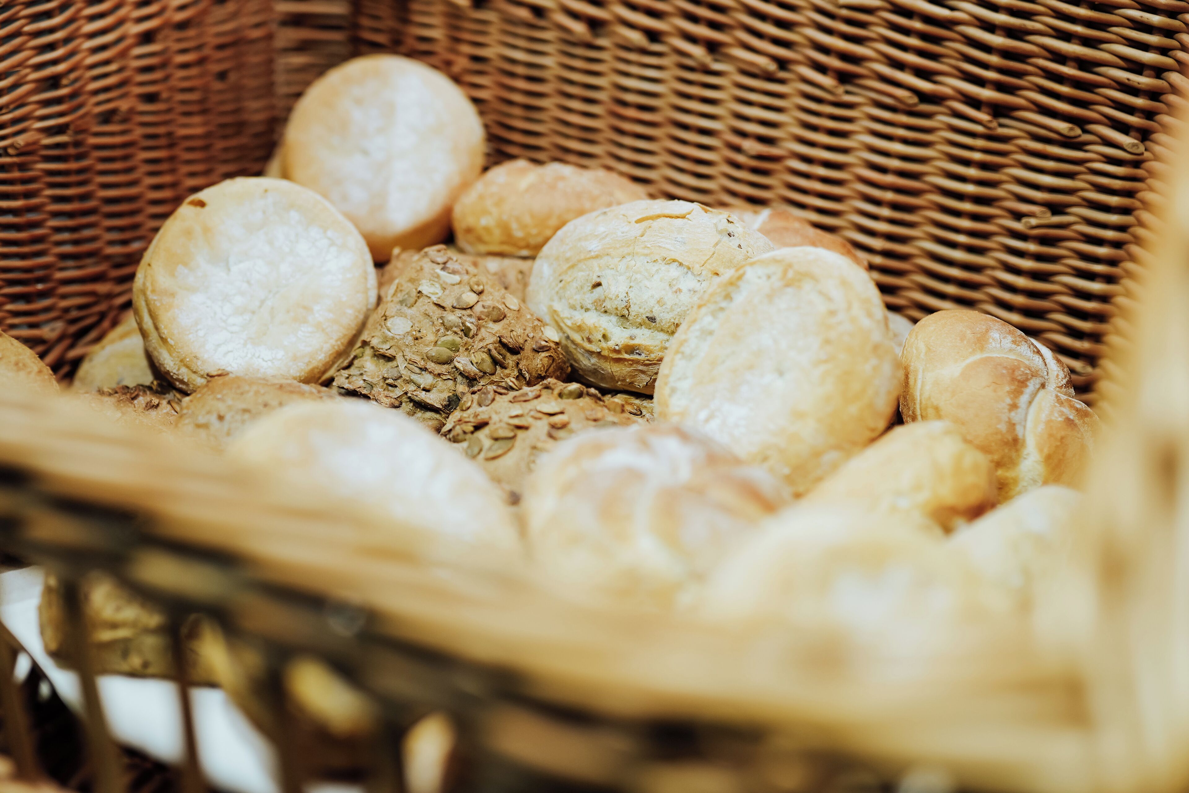 A wicker basket filled with various types of bread.