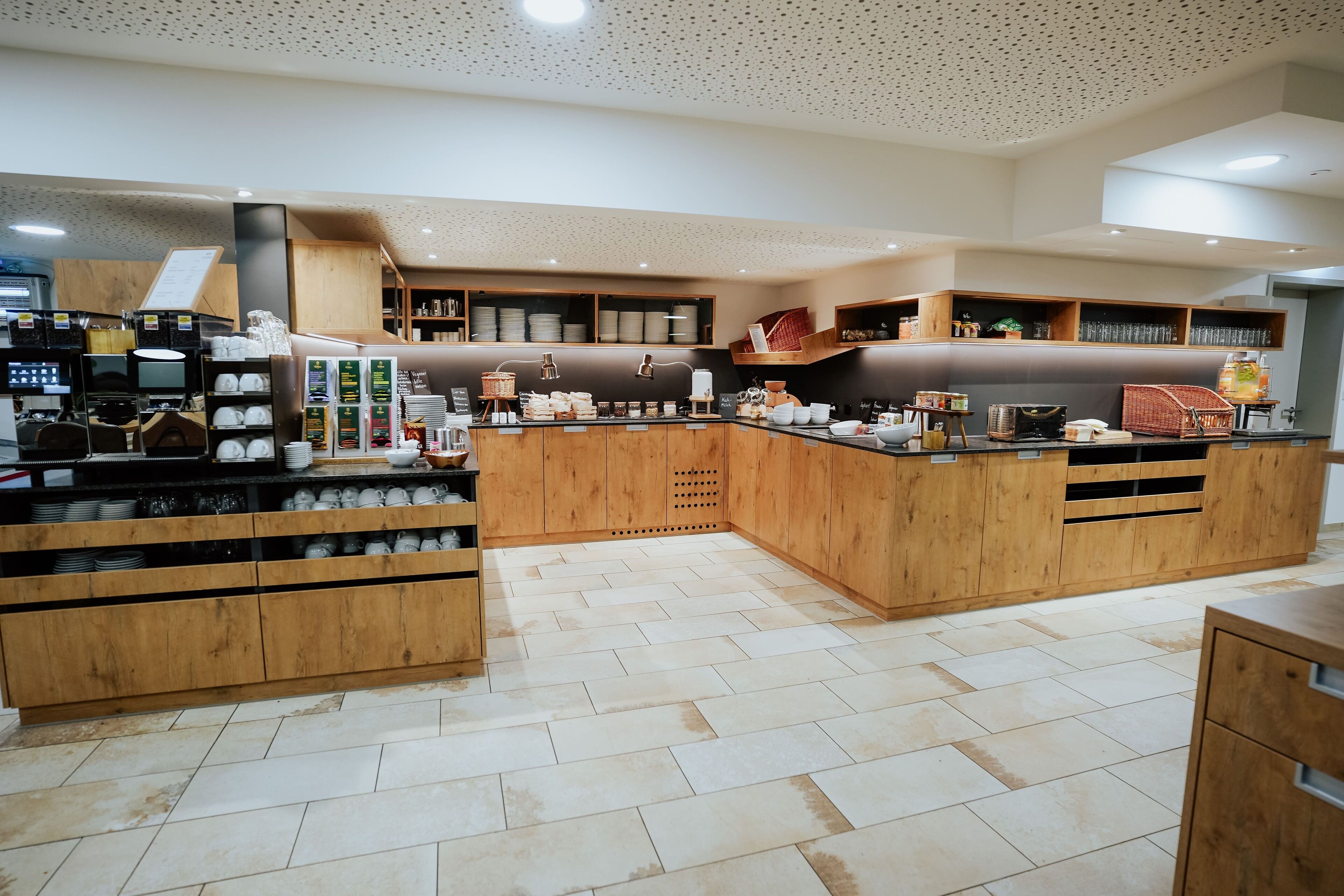 A modern kitchen with wooden cabinets, a coffee machine, and various kitchen utensils.
