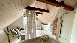 A bedroom with a sloped ceiling, a bed, a chair, a desk, and a wardrobe. - The farrier's yard (Hörby)