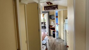A hallway with a wooden floor, a ceiling fan, and a TV mounted on the wall. - ‘Salamandre’ Mobile Home with Mountain Views, Shared Pool, and Air Conditioning (Sainte-Croix-du-Verdon)
