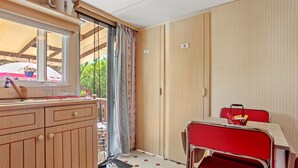 A compact kitchen with a window, a dining area with a table and chairs, and a door leading to an outdoor area.