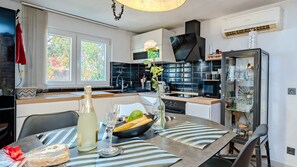 A modern kitchen with a dining area, featuring a large window, a built-in oven, and a glass cabinet.