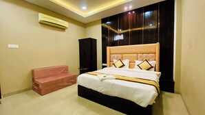 Hotellihuone, jossa on suuri sänky, vaaleanpunainen sohva ja tumma puinen pääty.