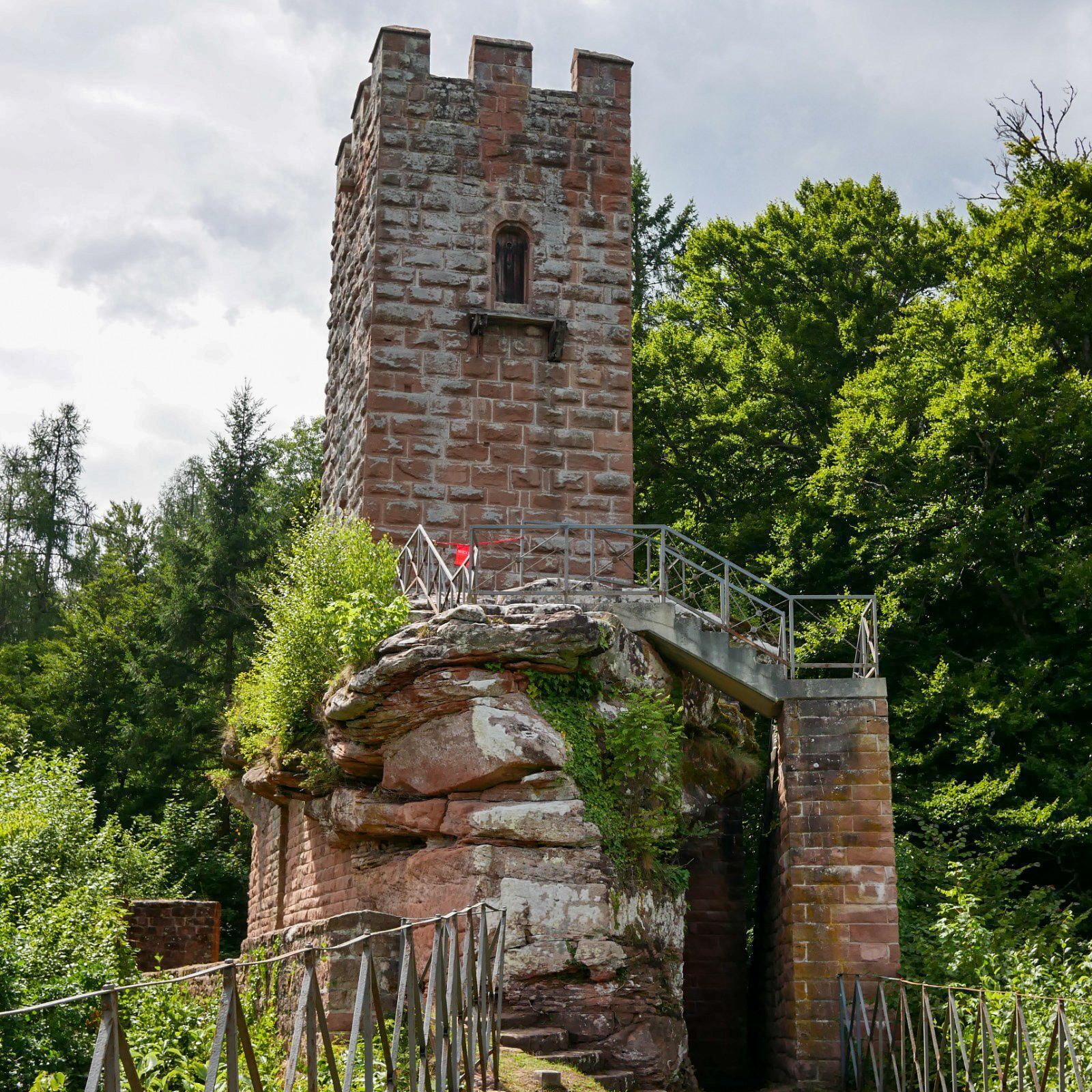 Een historische stenen toren met een smalle wenteltrap die naar een klein raam leidt.