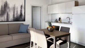 A modern kitchen with white cabinets, a stainless steel sink, and a fruit bowl on the dining table. - S02 - 4 PAX – TERRACE (LAVARONE)