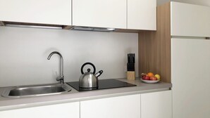 Una cocina moderna con un hervidor de acero inoxidable, un fregadero y un frutero sobre la encimera.
