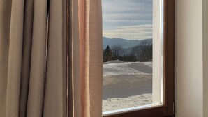 Una ventana con vistas a un paisaje nevado y montañas lejanas.