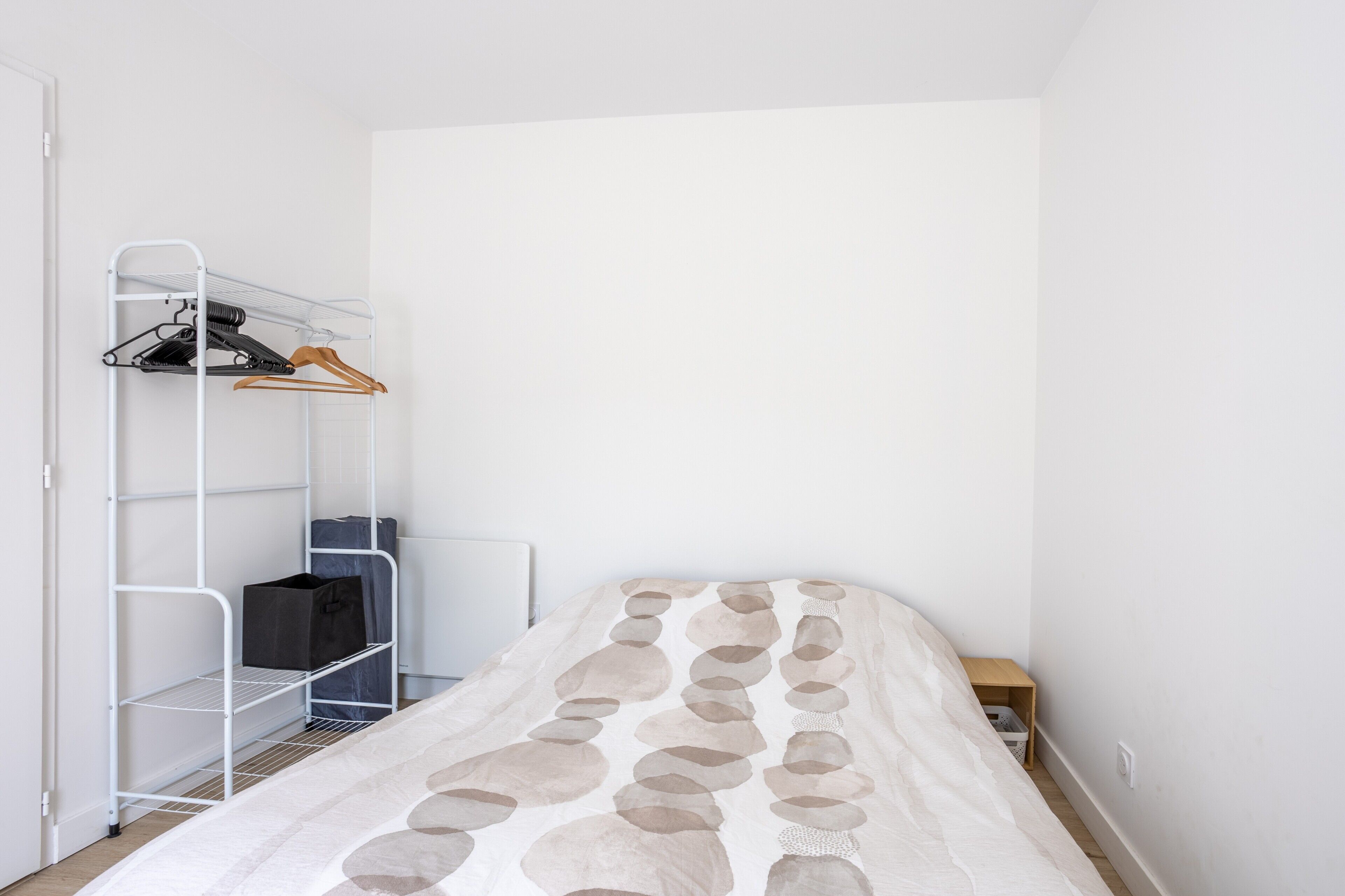 Une chambre à coucher avec un lit, une armoire blanche et une petite table de chevet.